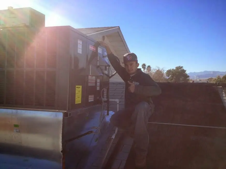 HVAC technician performing AC Tune-Up on a rooftop unit in Warren